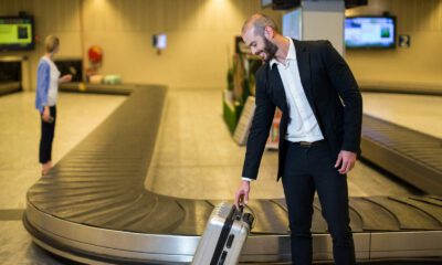 Homem sorridente pega mala na esteira do aeroporto