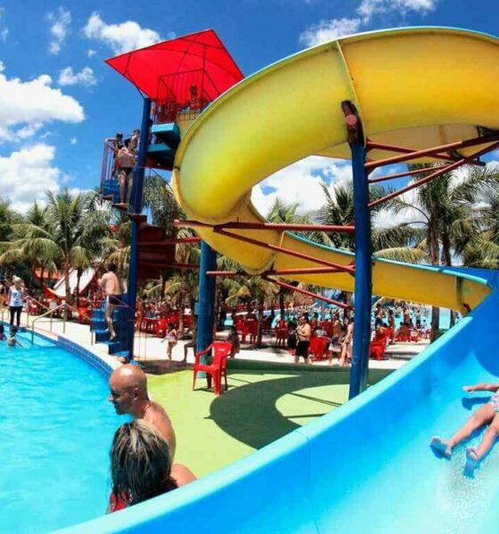 Parque aquático com toboáguas azuis, piscina e crianças escorregando