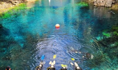 Lagoa misteriosa com água muito azul e mergulhadores com cilindros
