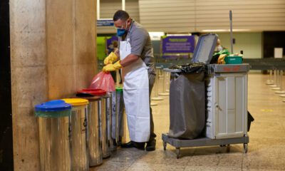 Trabalhador da limpeza retirando lixo da coleta seletiva no BH Airport